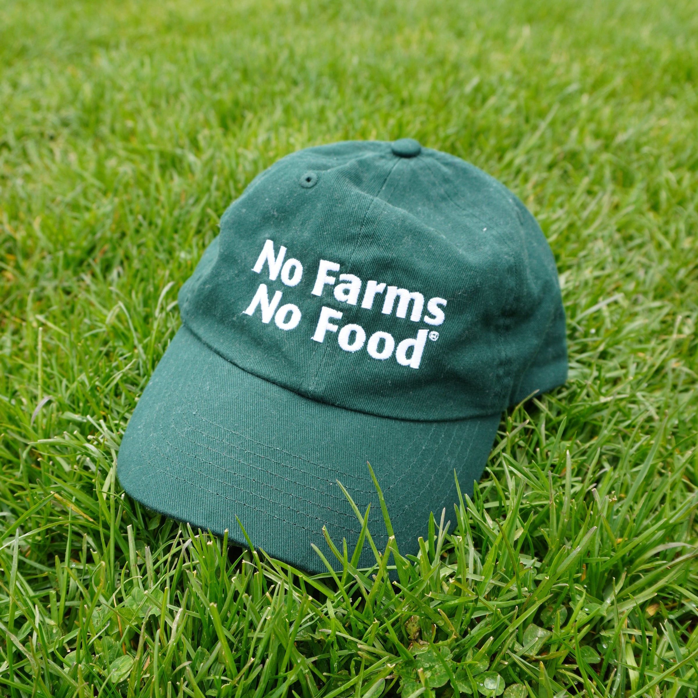 Green cap with 'No Farms No Food' text on grass
